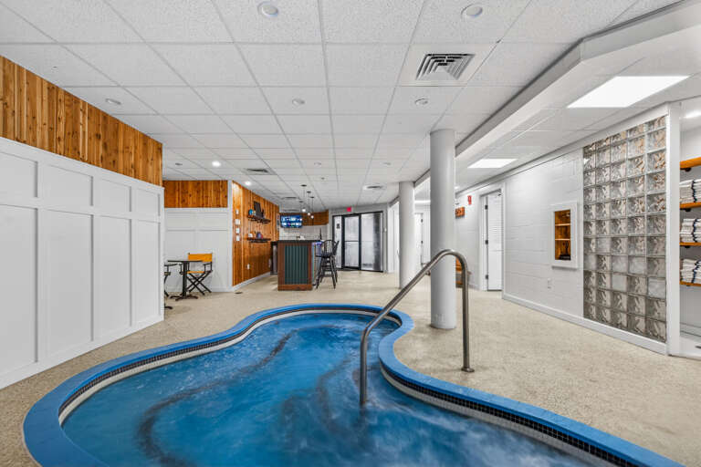 Indoor Pool With White Walls And Wood Paneling, Curving Corridor Beyond