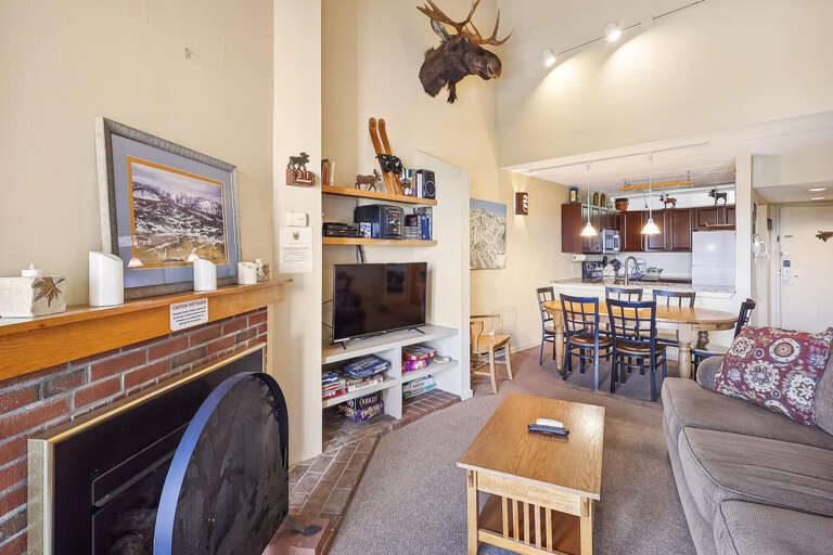 Living Area With Fireplace Flanked By Furniture, Flowing Into A Kitchen