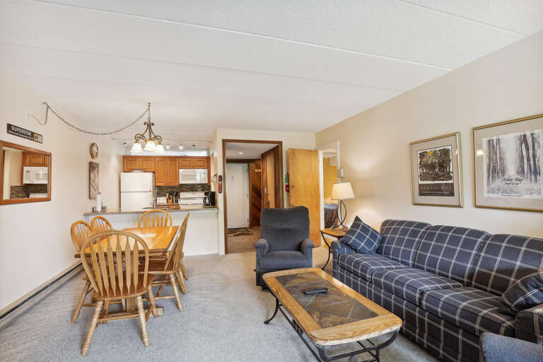 Interior View Featuring Furnished Living Space With Dining Set And Plaid Sofa, Leading To Kitchen