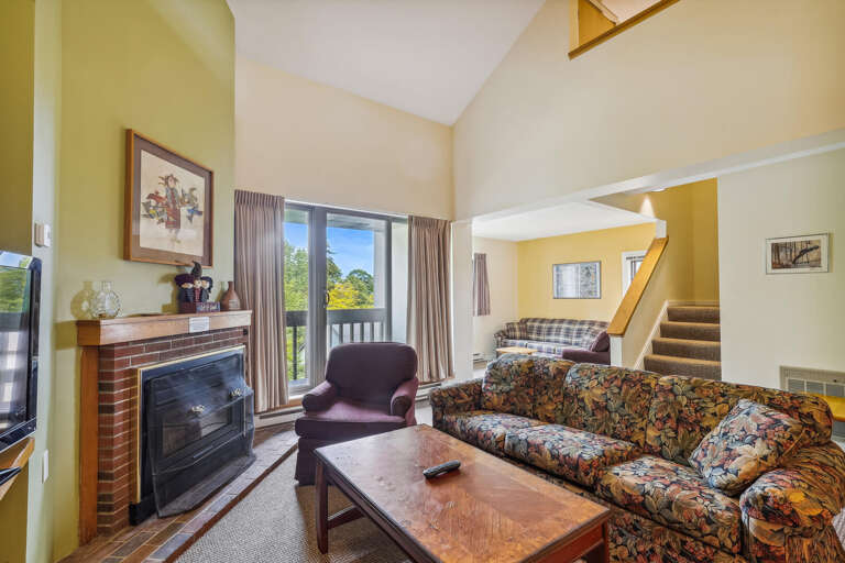 Living Room With Sofa, Chair, Fireplace, Staircase, And Balcony Doors