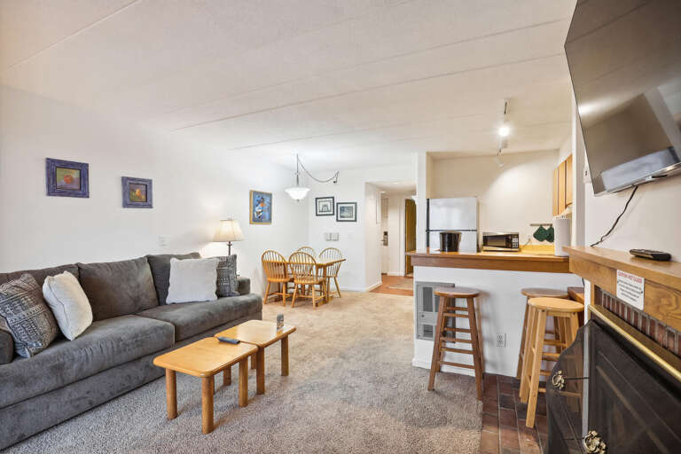 Spacious Living Space With Soft Sofa, Subtle Shades, And Sleek Kitchen Setup
