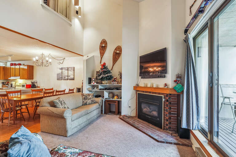 Spacious Split-level Living Space With Fireplace, Festive Decor, And Forest-facing Windows