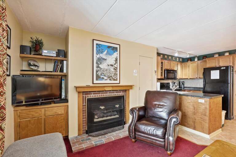 Living Space With Leather Chair, TV, Fireplace, And Kitchenette