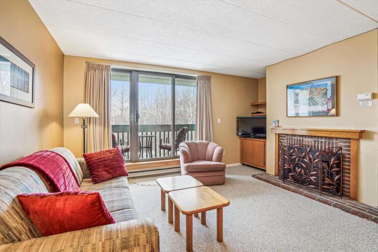 Vacation Rental Room With Sofa, Armchair, Fireplace, And Balcony View