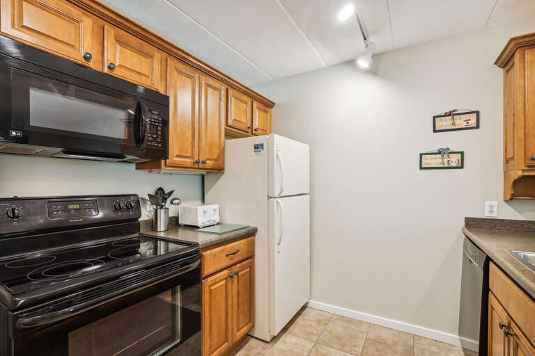 Vacation Rental Kitchen With Wooden Cabinets And White Appliances