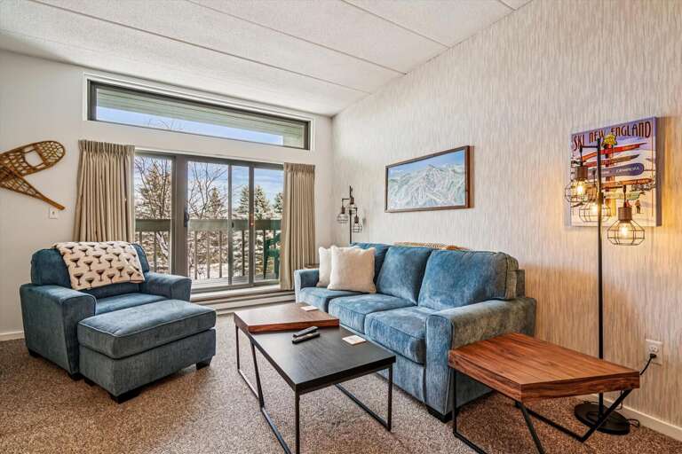 View Of A Serene Sitting Space In A Vacation Rental, Large Window Looking Out To Trees