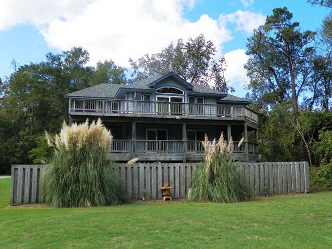 Two-story Residential Building With Balcony Surrounded By Grass And Fence