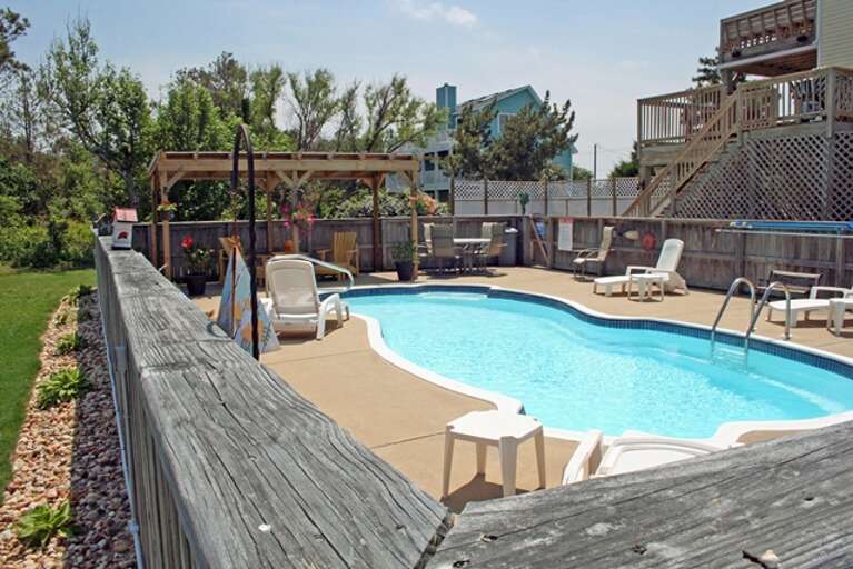 Outdoor Swimming Pool With Deck Chairs And A Wooden Fence Outdoor Swimming Pool With Deck Chairs And A Wooden Fence