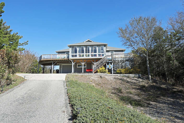 Suburban House With Driveway And Trees Under Blue Sky