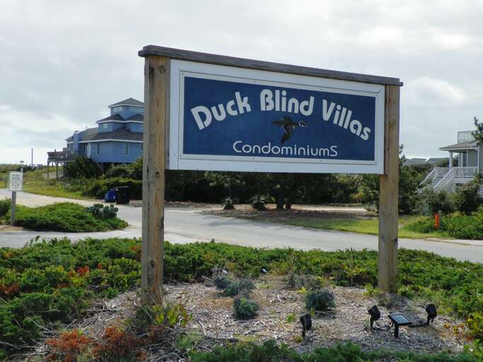 Sign For Duck Blind Villas Condominiums With Buildings In The Background