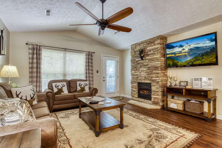 Living Space With Stone Fireplace, Plush Seating, And Ceiling Fan
