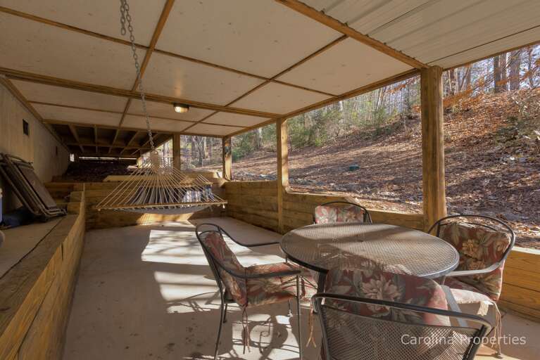Covered area under the lakeside deck with hot tub, hammock and table