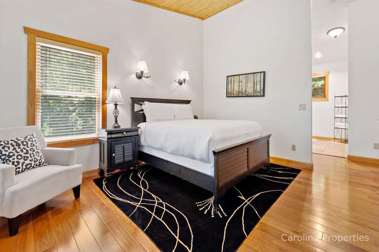 The second main level suite has a sleigh bed, cozy chair and plenty of windows for natural lighting
