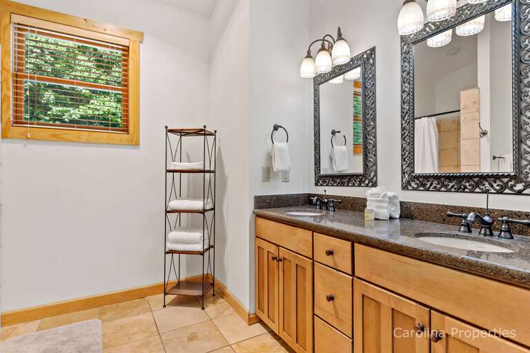 The adjoining full bathroom has a vanity with a double sink and plenty of storage. The walk-in shower is tiled and spacious