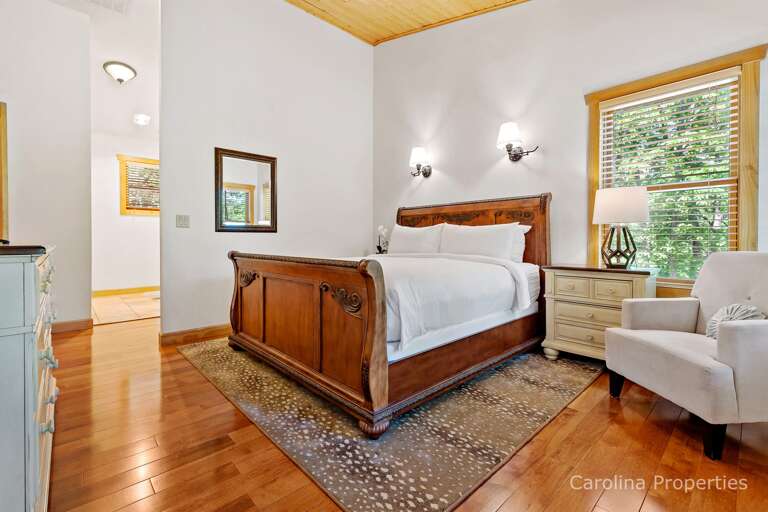 This main level suite has a sleigh bed, ceiling fan, a cozy chair and plenty of storage
