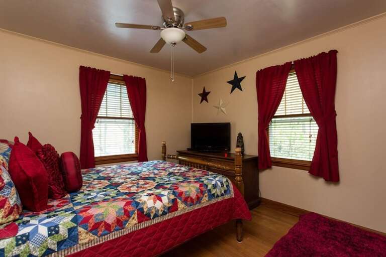 The bedroom with a queen bed has the addition of a TV.