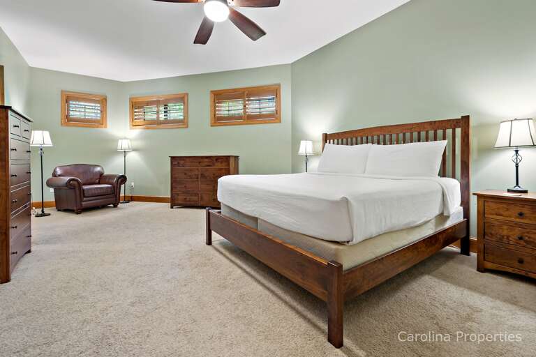 On the lower level is the second king bed master suite with a closet, bureaus, and a chair On the lower level is the second king bed master suite with a closet, bureaus, and a chair