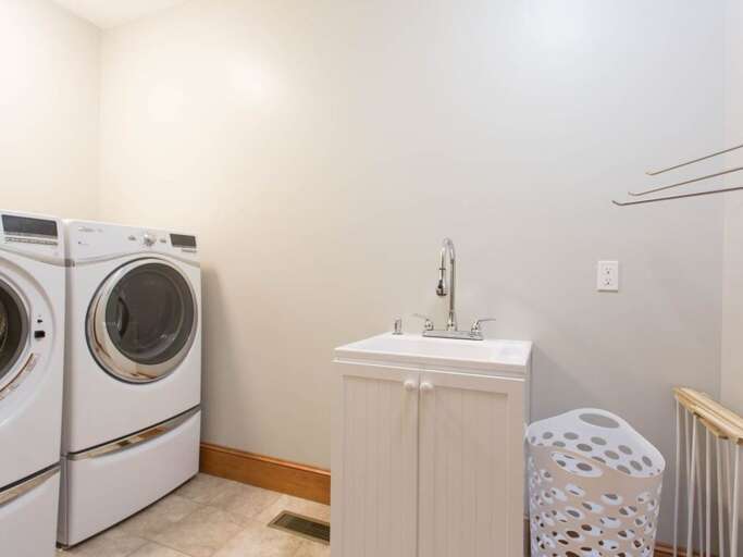 There is a laundry room with a full-size washer/dryer, sink, hangers, laundry basket, and drying rack There is a laundry room with a full-size washer/dryer, sink, hangers, laundry basket, and drying rack