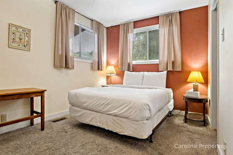 There are windows in the bedroom, a ceiling fan, and a door that leads to a covered deck.