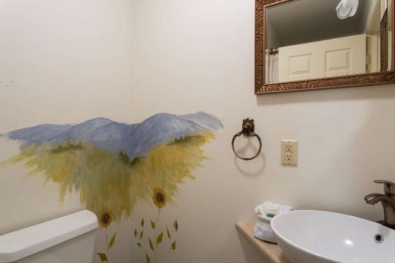 The half bath features a vessel sink and a wall painting of the mountains. The half bath features a vessel sink and a wall painting of the mountains.
