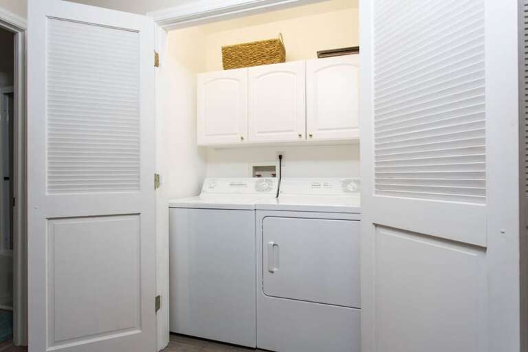 Open the doors to reveal the full-size washer/dryer and overhead storage.