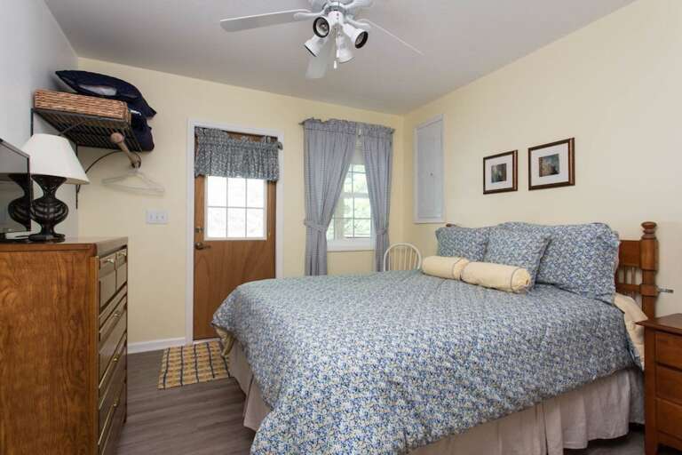 The third bedroom has a bureau, TV, window, ceiling fan, and door to the front of the home.