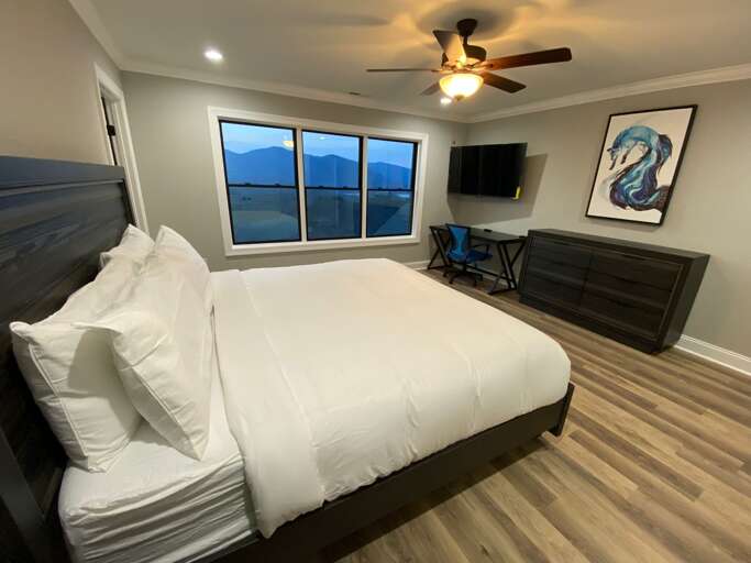 Cozy king bed, dresser and TV in the main level bedroom