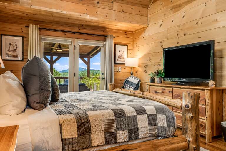 Cozy king bed with a TV, and doors leading to the deck.