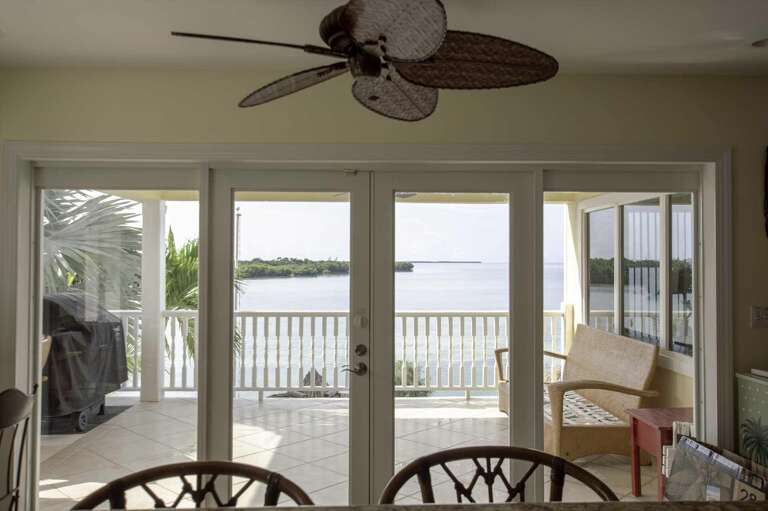Room Interior With Ceiling Fan Facing Balcony And Waterfront View
