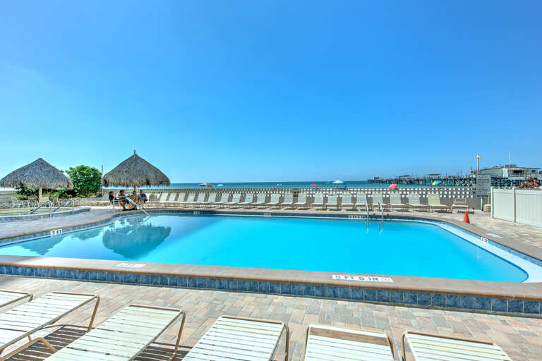 Crystal-clear pool with stunning ocean views and tropical thatched huts creating your perfect waterfront paradise escape.