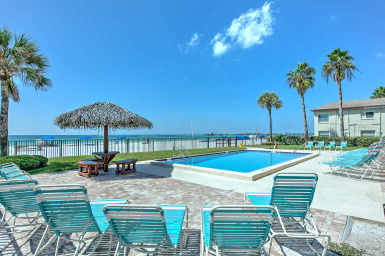 Beachfront pool area features crystal-clear waters, tropical palms, and direct ocean access for the ultimate coastal escape.