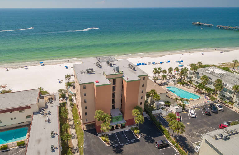 Beachfront property with direct access to pristine white sand beaches and emerald Gulf waters, featuring swimming pool and tropical palm landscaping.