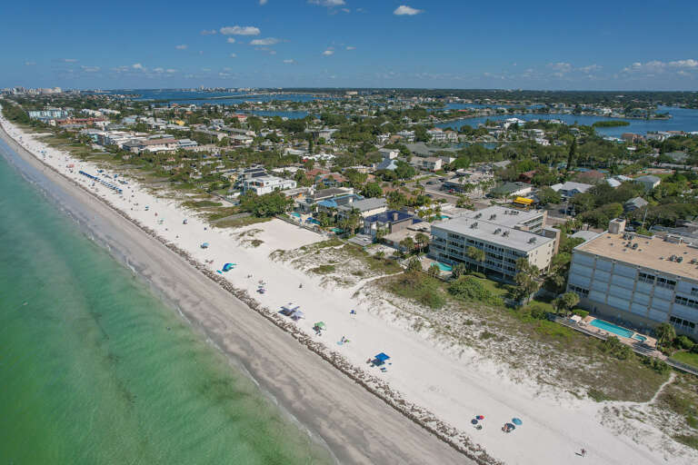 Stunning beachfront location with pristine white sand and crystal-clear turquoise waters stretching along the coast.
