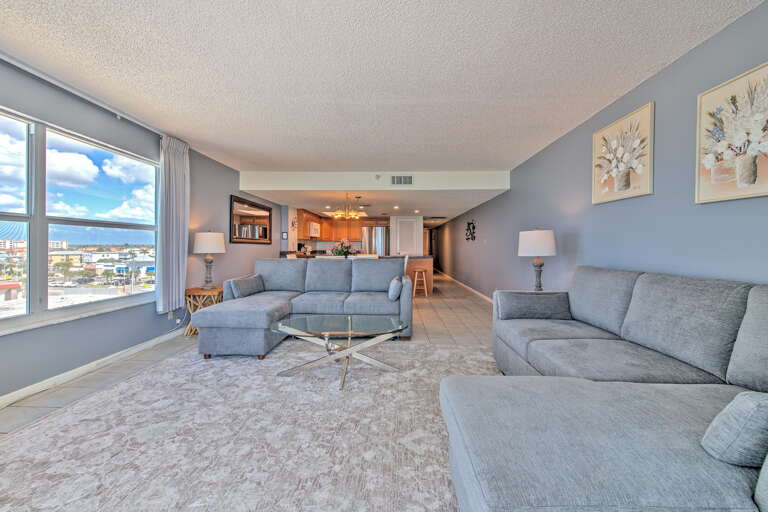 Relax in your spacious living room featuring plush sectional seating and stunning city views through floor-to-ceiling windows.