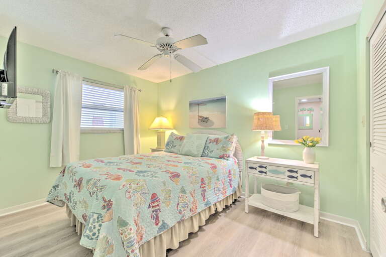 Relax in this charming seafoam bedroom with tropical bedding, warm bedside lighting, and coastal touches that create your perfect beach getaway sanctuary.