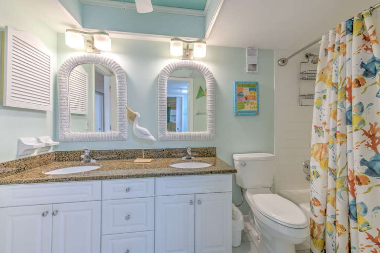 Step into your coastal-themed bathroom with dual vanities, granite counters, and cheerful tropical accents that make your morning routine a vacation experience.