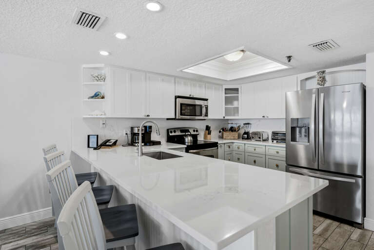 Your fully equipped modern kitchen features sleek white cabinets, stainless steel appliances, and a spacious island perfect for cooking memorable meals.