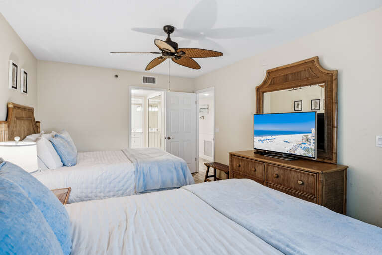 Relax in your tropical-inspired bedroom with twin beds, coastal furnishings, and entertainment center for perfect beach vacation comfort.