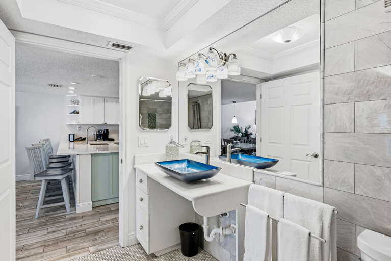 Your elegant dual-sink bathroom features stunning blue vessel bowls and opens beautifully to your bright kitchen space.