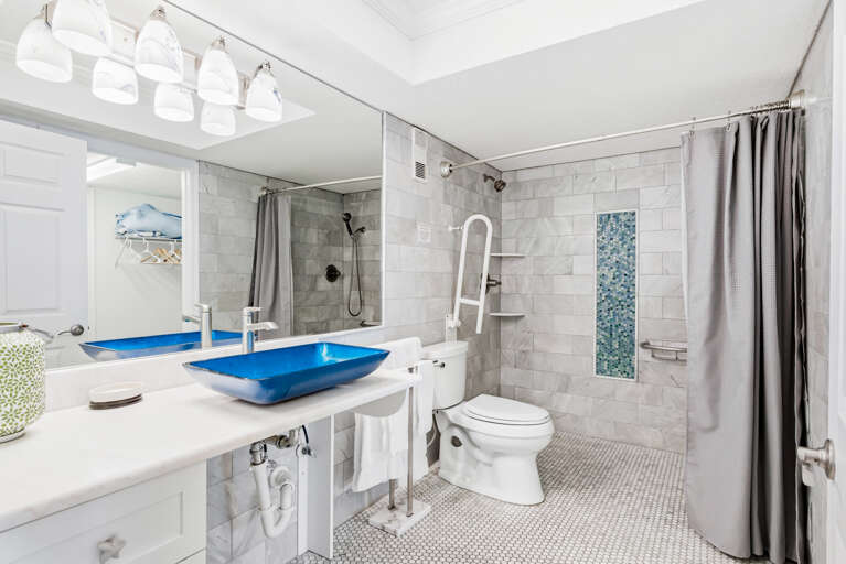 Step into your spa-like retreat with marble tiles, a striking blue vessel sink, and rainfall shower for pure relaxation.
