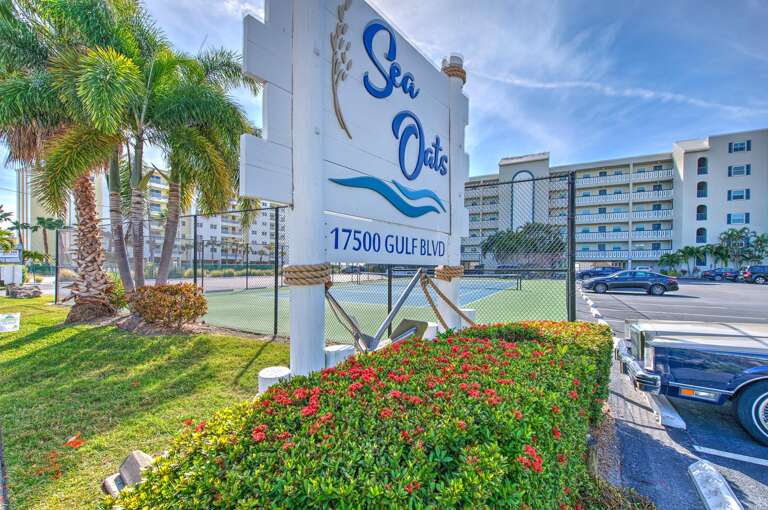 Sea Oats complex entrance sign surrounded by lush tropical landscaping and palm trees, marking your arrival to this beachfront destination.