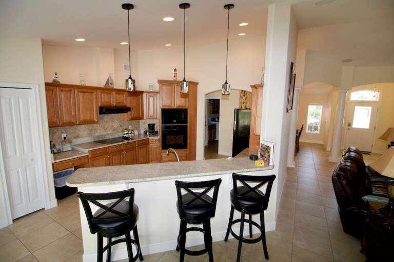 Spacious Kitchen With Bar Stools And Pendant Lighting