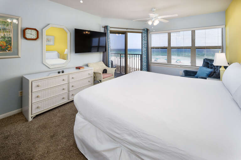 The master bedroom has a king-sized bed, rocker/recliner, Smart TV and a sliding glass door to the balcony.