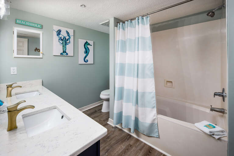 This bathroom has the shower / tub combo & beach themed décor.