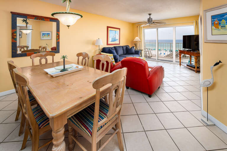 Bright Beachfront Living Area With Dining Set, Sofas, And Balcony View
