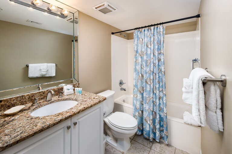 Accessible from the hallway and guest bedroom, the hall bath features granite countertops and stainless steel fixtures.