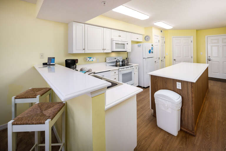 This bright, white kitchen has all the necessities including a microwave, coffee maker, and a blender.