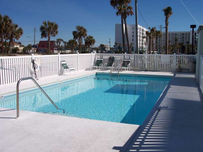 The fenced-in pool is located in front of the building's parking area.  A small building next to it houses convenient bathrooms.