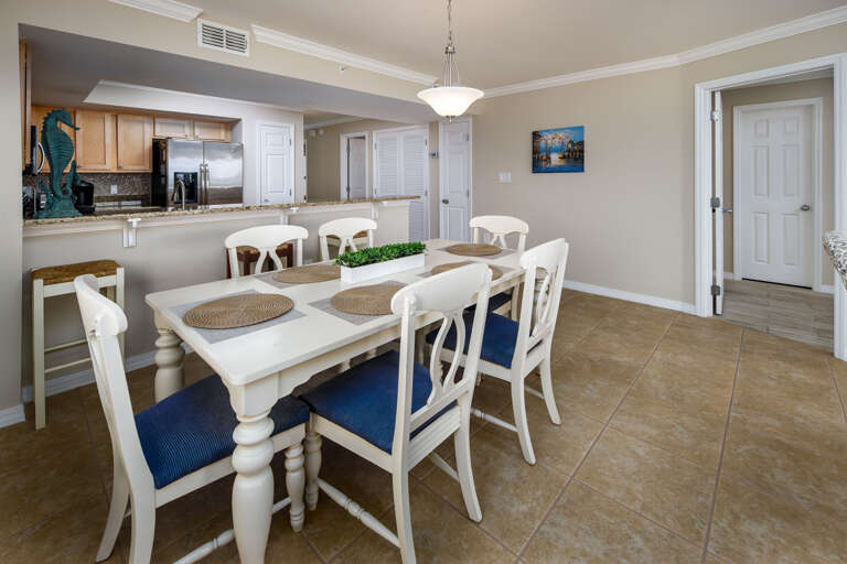Dining area that has 6 chairs at the table and 3 bar stools for the kitchen bar area
