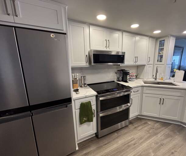 Modern kitchen featuring marble countertops, a spacious island, and updated stainless steel appliances.